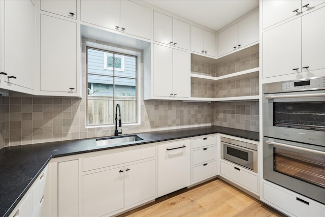 3755 Rice Blvd, Houston, TX 77005 - kitchen with stainless steel appliances, a sink, dark countertops, and white cabinets