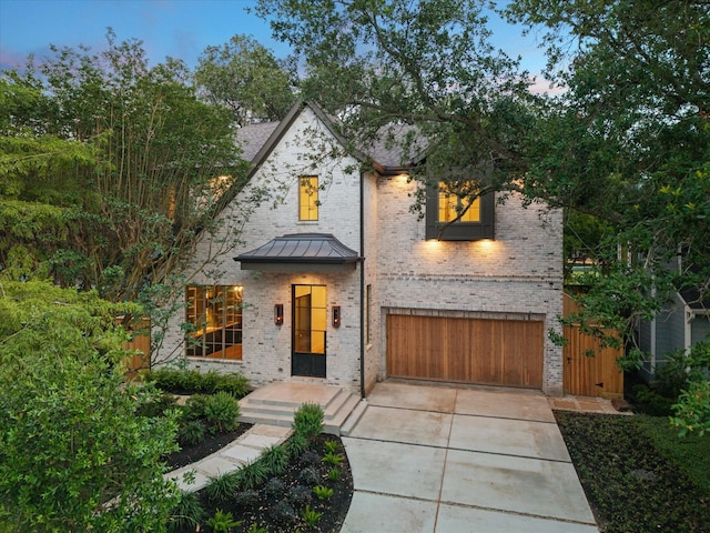 3755 Rice Blvd, Houston, TX 77005 - view of front of house with brick siding, an attached garage, driveway, and a standing seam roof