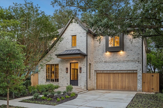 3755 Rice Blvd, Houston, TX 77005 - view of front of home with brick siding, a garage, driveway, and a standing seam roof
