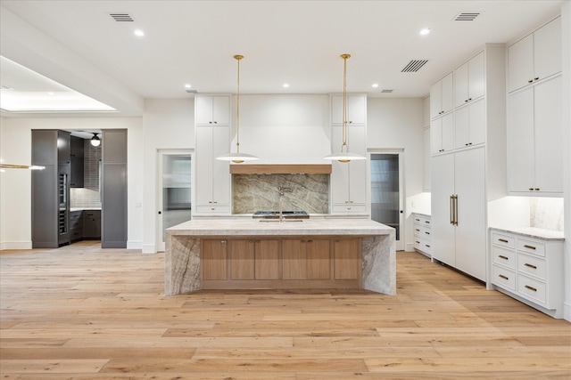 3755 Rice Blvd, Houston, TX 77005 - kitchen with backsplash, light wood-type flooring, a spacious island, recessed lighting, and white cabinets