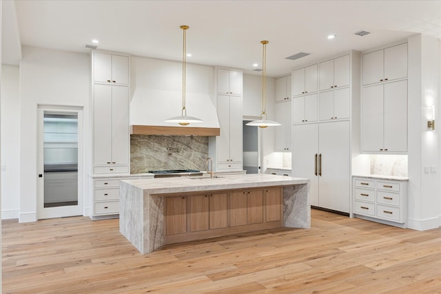 3755 Rice Blvd, Houston, TX 77005 - kitchen with decorative backsplash, light wood-style flooring, a kitchen island with sink, white cabinets, and recessed lighting