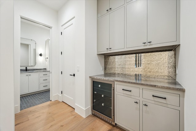 3755 Rice Blvd, Houston, TX 77005 - bar with wine cooler, light wood-style floors, tasteful backsplash, a sink, and baseboards