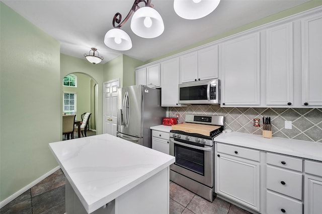 12010 Piney Bend Dr, Tomball, TX 77375 - kitchen with appliances with stainless steel finishes, arched walkways, decorative backsplash, a center island, and white cabinets