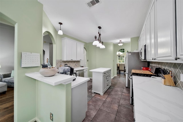 12010 Piney Bend Dr, Tomball, TX 77375 - kitchen with appliances with stainless steel finishes, a kitchen island, decorative backsplash, arched walkways, and white cabinetry