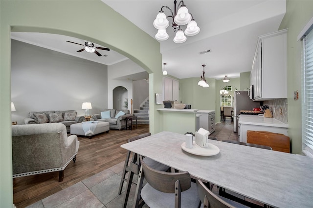 12010 Piney Bend Dr, Tomball, TX 77375 - tiled dining space with arched walkways, a ceiling fan, stairway, a chandelier, and crown molding