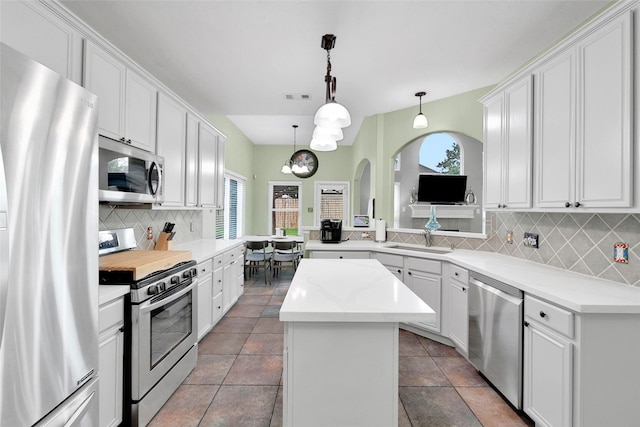 12010 Piney Bend Dr, Tomball, TX 77375 - kitchen featuring appliances with stainless steel finishes, arched walkways, a kitchen island, a sink, and healthy amount of natural light