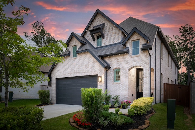 221 Sky Top Dr, Montgomery, TX 77316 - french country style house featuring driveway, an attached garage, brick siding, and roof with shingles