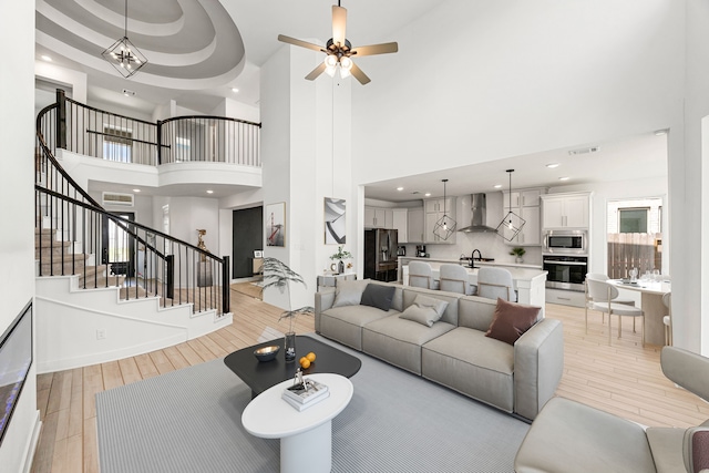 31207 Hastings Creek Ln, Fulshear, TX 77441 - living area with light wood-style floors, stairs, a towering ceiling, ceiling fan, and baseboards