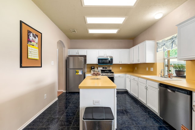 4907 Sienna Heights Ln, Pasadena, TX 77505 - kitchen featuring appliances with stainless steel finishes, a sink, light countertops, arched walkways, and white cabinetry