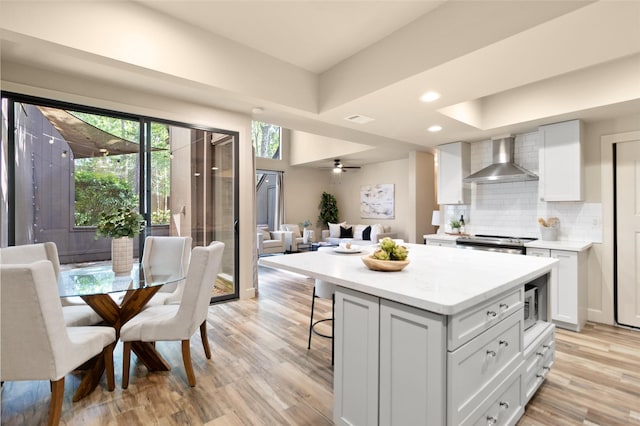 137 Litchfield Ln, Houston, TX 77024 - kitchen featuring wall chimney exhaust hood, open floor plan, light wood-style floors, appliances with stainless steel finishes, and decorative backsplash