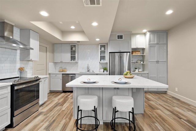 137 Litchfield Ln, Houston, TX 77024 - kitchen with stainless steel appliances, wall chimney range hood, baseboards, a breakfast bar, and recessed lighting