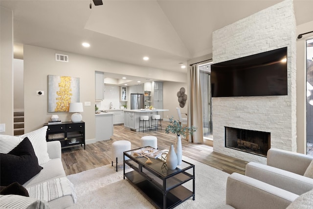 137 Litchfield Ln, Houston, TX 77024 - living area featuring light wood-type flooring, a stone fireplace, vaulted ceiling, and recessed lighting