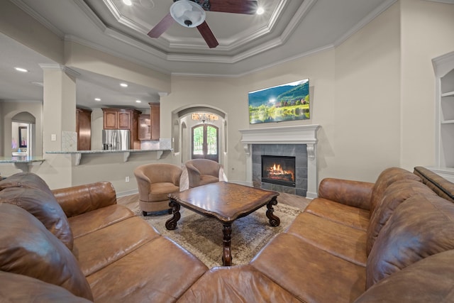 261 Ridge Lake Dr, Montgomery, TX 77316 - living area with ornamental molding, a ceiling fan, a tiled fireplace, light wood-style floors, and arched walkways