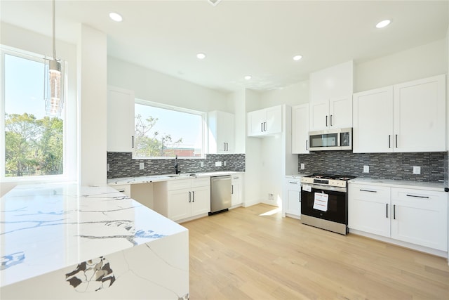 3508 Sauer St, Houston, TX 77004 - kitchen with appliances with stainless steel finishes, light stone counters, tasteful backsplash, light wood-style floors, and white cabinetry