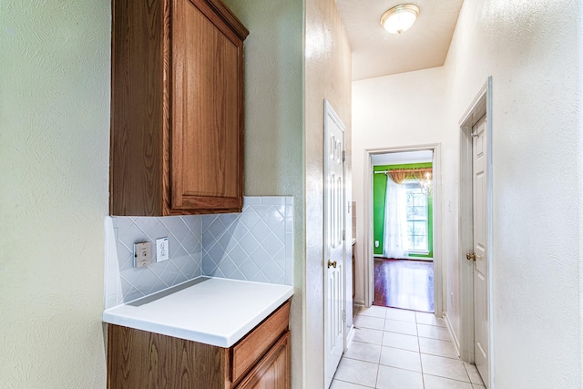 2207 Desert Vine Ct, Sugar Land, TX 77498 - kitchen with brown cabinetry, light tile patterned flooring, decorative backsplash, light countertops, and a textured wall