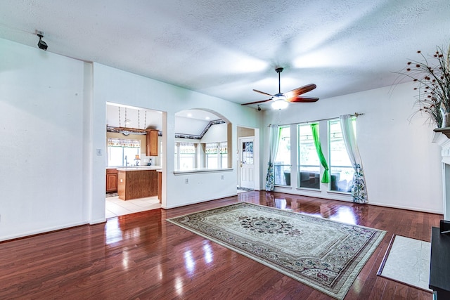 2207 Desert Vine Ct, Sugar Land, TX 77498 - living area with a ceiling fan, arched walkways, a textured ceiling, light wood-style floors, and a fireplace with flush hearth