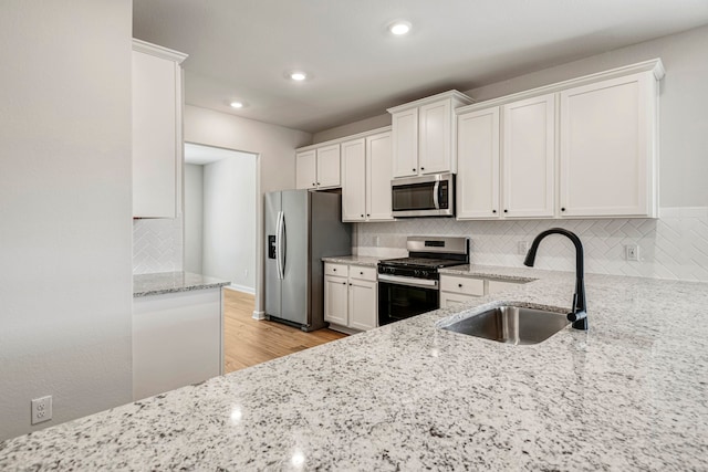 15667 Honey Cove Dr, Conroe, TX 77303 - kitchen with appliances with stainless steel finishes, a sink, decorative backsplash, white cabinetry, and recessed lighting