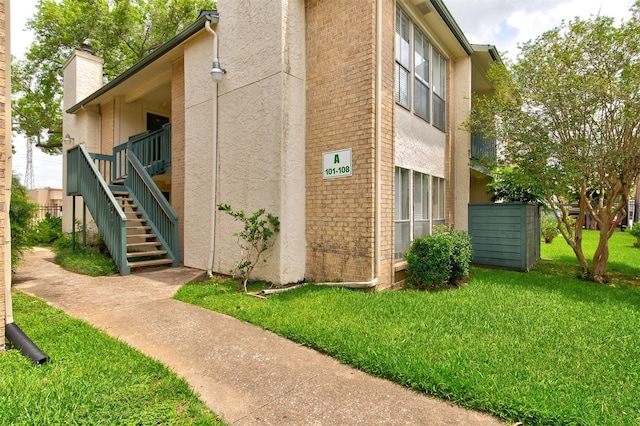 250 El Dorado Blvd Unit 103, Houston, TX 77598 - view of side of home featuring a lawn, a chimney, stairs, and stucco siding