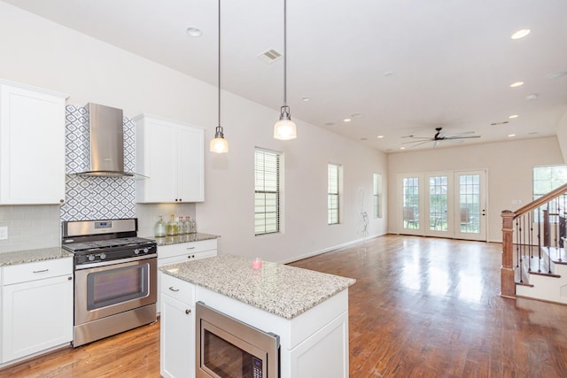 1404 W 26th St Unit C, Houston, TX 77008 - kitchen featuring appliances with stainless steel finishes, wall chimney exhaust hood, light wood-type flooring, open floor plan, and ceiling fan