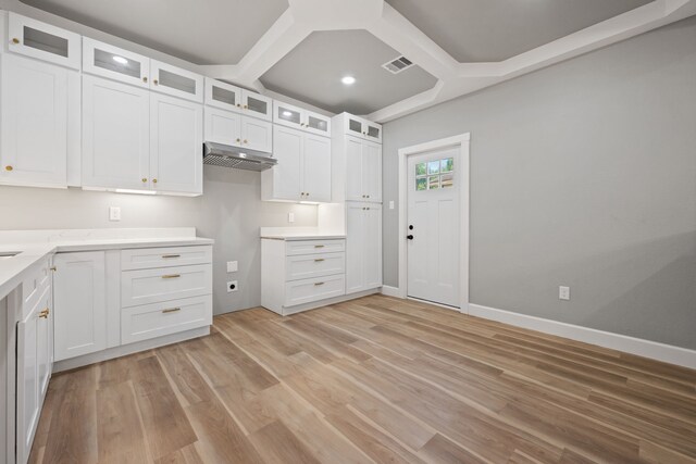 7024 Avenue Ave E, Houston, TX 77011 - kitchen with light wood-style floors, white cabinets, under cabinet range hood, glass insert cabinets, and coffered ceiling