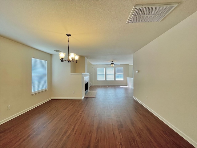 21807 Olympia Springs Ln, Katy, TX 77449 - unfurnished living room featuring dark wood-type flooring, baseboards, a chandelier, and a fireplace with raised hearth