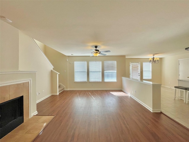 21807 Olympia Springs Ln, Katy, TX 77449 - unfurnished living room featuring a chandelier, stairway, wood finished floors, and a tiled fireplace