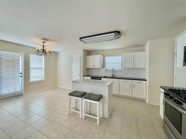 21807 Olympia Springs Ln, Katy, TX 77449 - kitchen with stainless steel gas stove, tasteful backsplash, light tile patterned flooring, a chandelier, and a textured ceiling
