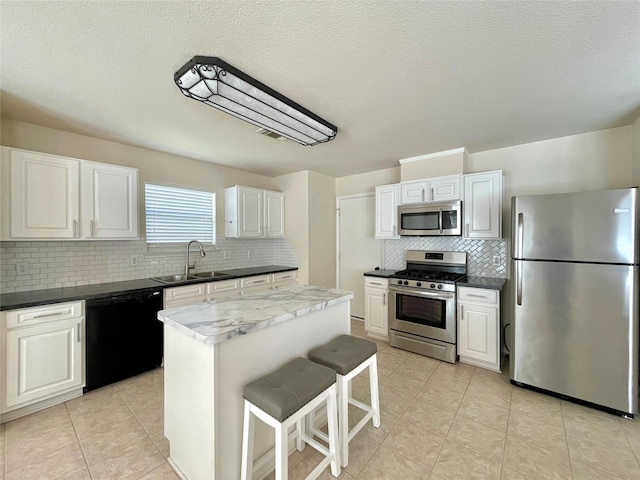 21807 Olympia Springs Ln, Katy, TX 77449 - kitchen with appliances with stainless steel finishes, a sink, tasteful backsplash, a center island, and white cabinets