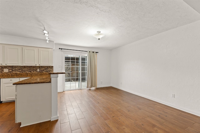 14721 Perthshire Rd, Houston, TX 77079 - kitchen featuring a textured ceiling, white cabinetry, wood finished floors, baseboards, and a peninsula