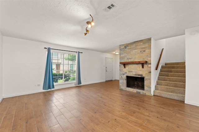 14721 Perthshire Rd, Houston, TX 77079 - unfurnished living room with a textured ceiling, stairs, wood finished floors, a large fireplace, and baseboards