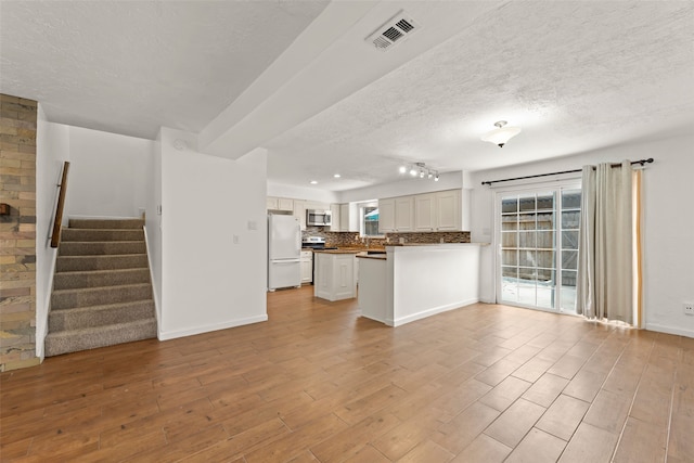 14721 Perthshire Rd, Houston, TX 77079 - unfurnished living room featuring a textured ceiling, light wood finished floors, stairway, healthy amount of natural light, and baseboards