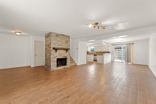 14721 Perthshire Rd, Houston, TX 77079 - unfurnished living room with a textured ceiling, light wood finished floors, baseboards, and a fireplace