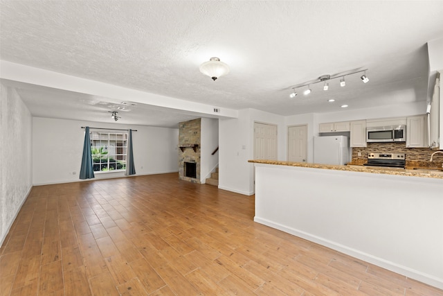 14721 Perthshire Rd, Houston, TX 77079 - unfurnished living room featuring light wood-style floors, stairs, a sink, a textured ceiling, and baseboards