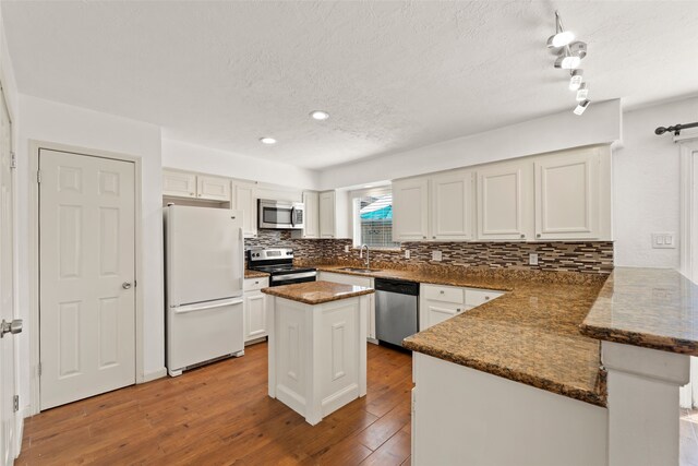 14721 Perthshire Rd, Houston, TX 77079 - kitchen featuring stainless steel appliances, a peninsula, backsplash, a sink, and wood-type flooring