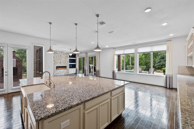 211 Twilight Toast Dr, Conroe, TX 77304 - kitchen featuring a fireplace, open floor plan, a sink, dark wood-type flooring, and light stone countertops