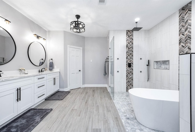 17706 August Meadows Ln, Spring, TX 77379 - full bathroom with tiled shower, double vanity, a soaking tub, baseboards, and wood finished floors