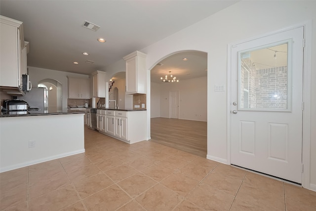 24511 Peroni Dr, Richmond, TX 77406 - kitchen featuring dark countertops, arched walkways, light tile patterned floors, a chandelier, and recessed lighting