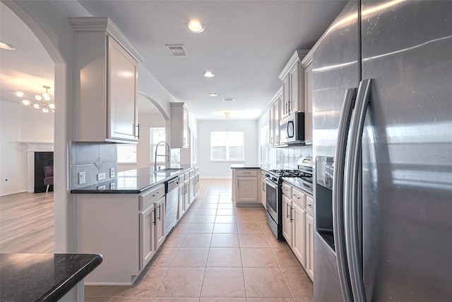 24511 Peroni Dr, Richmond, TX 77406 - kitchen with stainless steel appliances, decorative backsplash, a sink, recessed lighting, and arched walkways