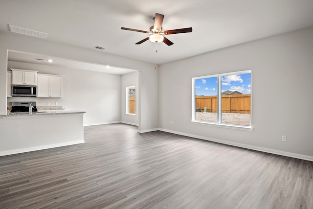 15695 Honey Cove Dr, Conroe, TX 77303 - unfurnished living room with wood finished floors, ceiling fan, and baseboards