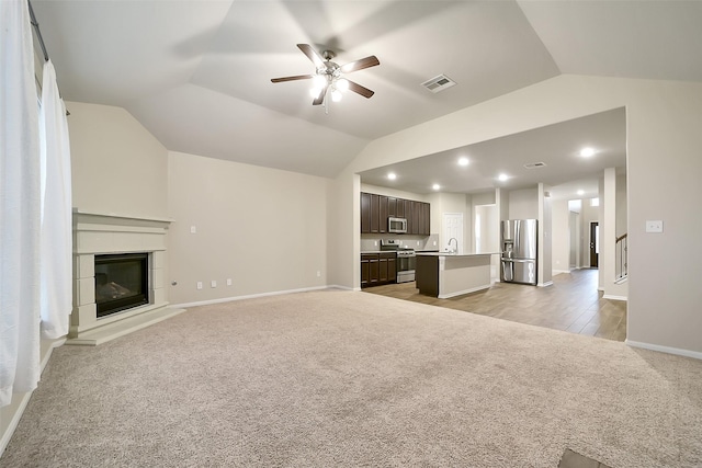 4502 Kayden Berry Ct, Rosenberg, TX 77471 - unfurnished living room with light colored carpet, vaulted ceiling, baseboards, ceiling fan, and a glass covered fireplace