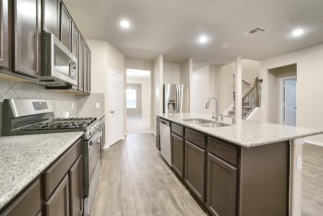 4502 Kayden Berry Ct, Rosenberg, TX 77471 - kitchen featuring appliances with stainless steel finishes, a sink, light wood finished floors, baseboards, and backsplash