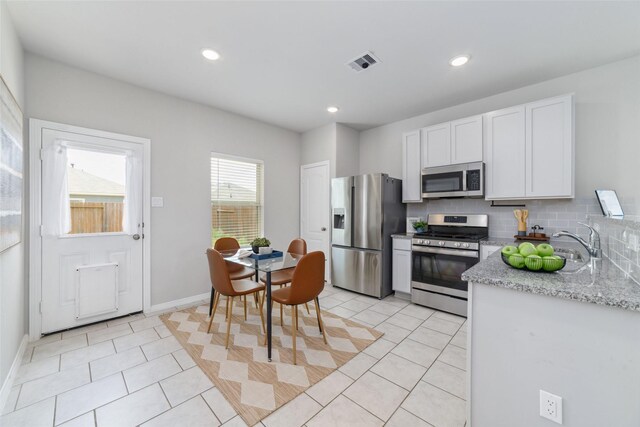 25807 Boxwood Hedge Ln, Tomball, TX 77375 - kitchen with stainless steel appliances, white cabinetry, light tile patterned floors, backsplash, and recessed lighting
