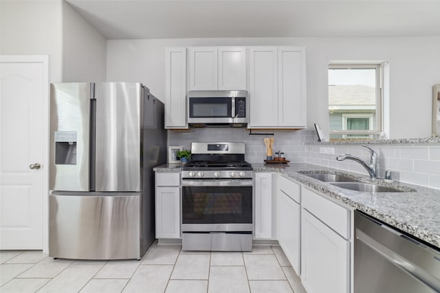 25807 Boxwood Hedge Ln, Tomball, TX 77375 - kitchen with stainless steel appliances, a sink, light stone counters, tasteful backsplash, and white cabinets