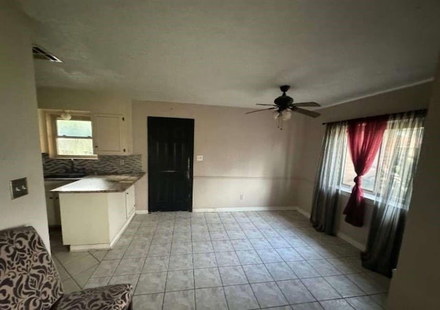 718 Westbury St, West Orange, TX 77630 - kitchen with white cabinetry, decorative backsplash, a ceiling fan, baseboards, and light tile patterned flooring
