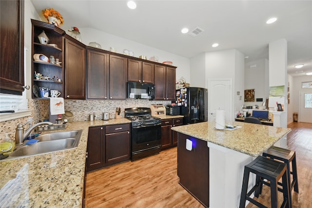 2209 Parker Ct, Brenham, TX 77833 - kitchen with black appliances, a sink, dark brown cabinets, a kitchen island, and a kitchen bar