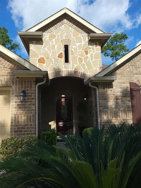 17023 Tallgrass Prairie Ln, Humble, TX 77346 - view of exterior entry with stone siding, an attached garage, and brick siding