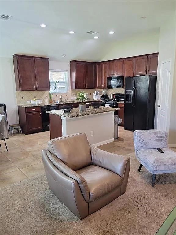 17023 Tallgrass Prairie Ln, Humble, TX 77346 - kitchen with black appliances, a center island, decorative backsplash, light stone counters, and recessed lighting
