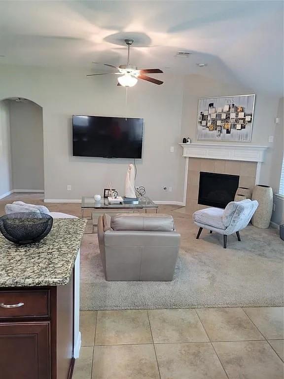 17023 Tallgrass Prairie Ln, Humble, TX 77346 - living room with a ceiling fan, a tile fireplace, arched walkways, light tile patterned flooring, and baseboards