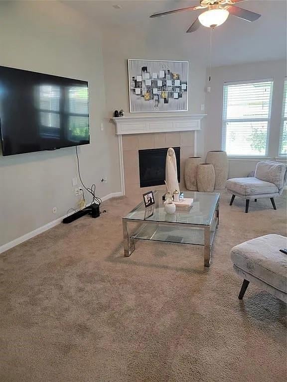 17023 Tallgrass Prairie Ln, Humble, TX 77346 - carpeted living room featuring a tile fireplace, ceiling fan, and baseboards