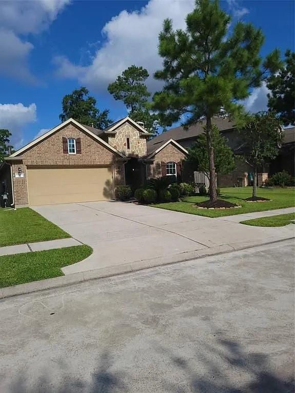 17023 Tallgrass Prairie Ln, Humble, TX 77346 - view of front of home featuring an attached garage, concrete driveway, stone siding, and a front lawn